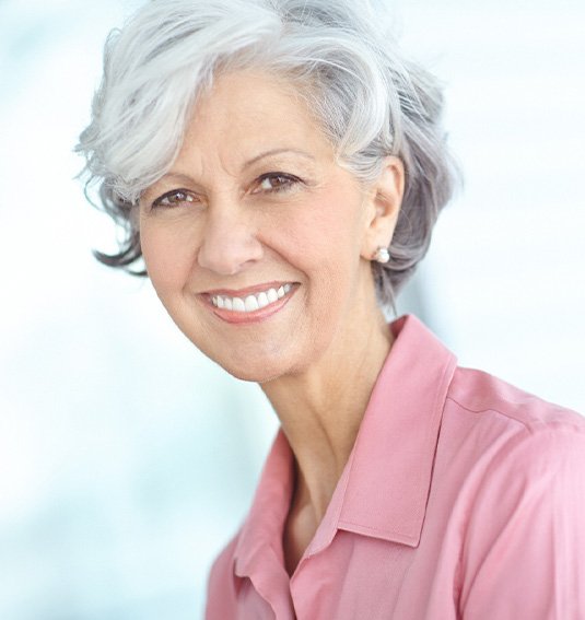 Woman in pink shirt with gray hair smiling