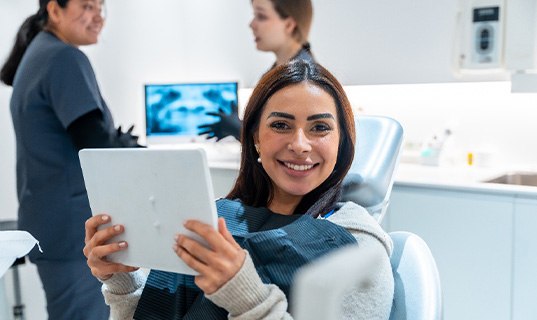 Woman smiling while holding handheld mirror