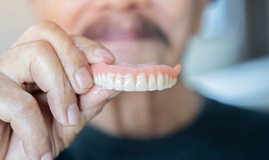 Man holding a full upper denture