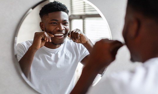Man smiling while flossing his teeth