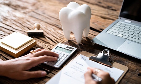 Patient calculating cost on desk with laptop
