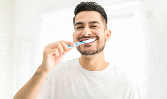 Man smiling while brushing teeth