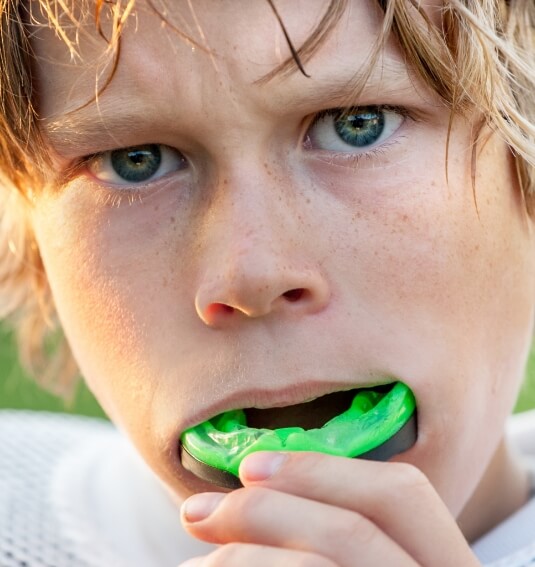 Teen placing a green athletic mouthguard