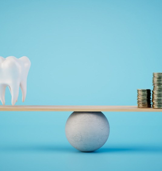 A ceramic model tooth and a stack of coins on a balance beam