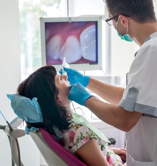 Dentist and dental patient looking at images capture by intraoral camera