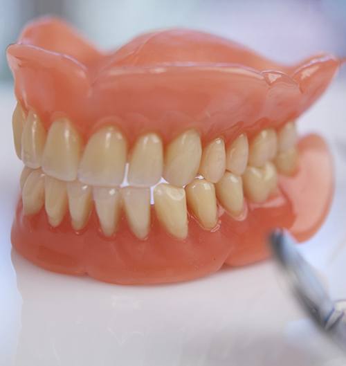Close-up of dentures in Des Plaines, IL next to dental instruments