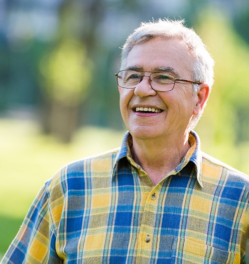 Senior man with glasses outside and smiling
