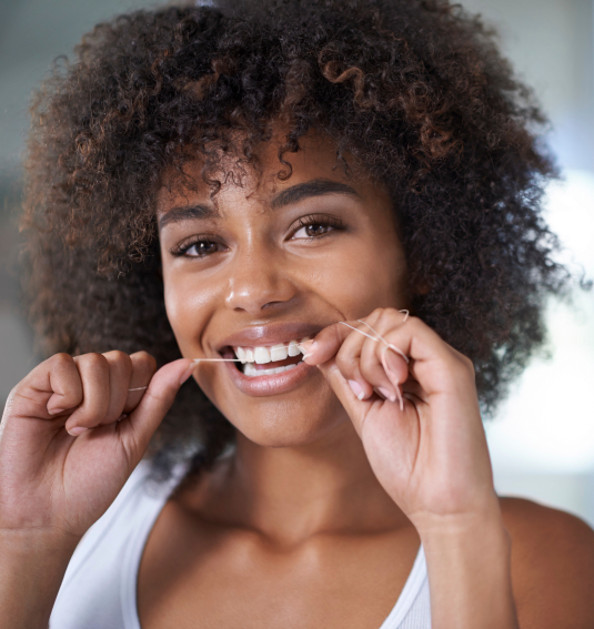 Woman flossing to prevent dental emergencies