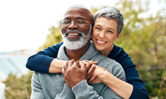 Couple smiling and hugging outside