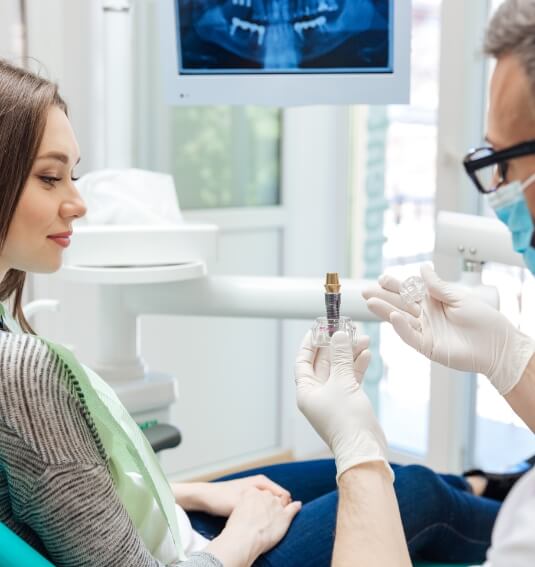 Dentist using model to explain the four step dental implant process