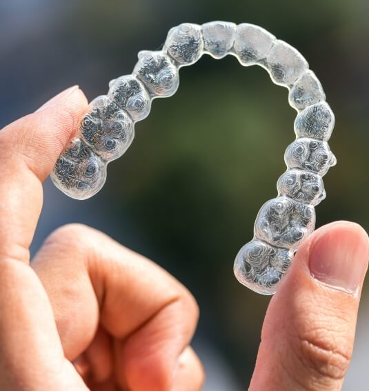 Hand holding an Invisalign tray