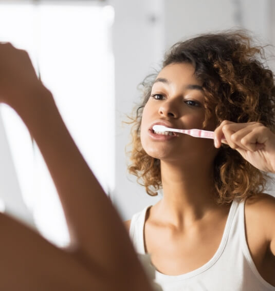 Woman brushing teeth after wisdom tooth extraction