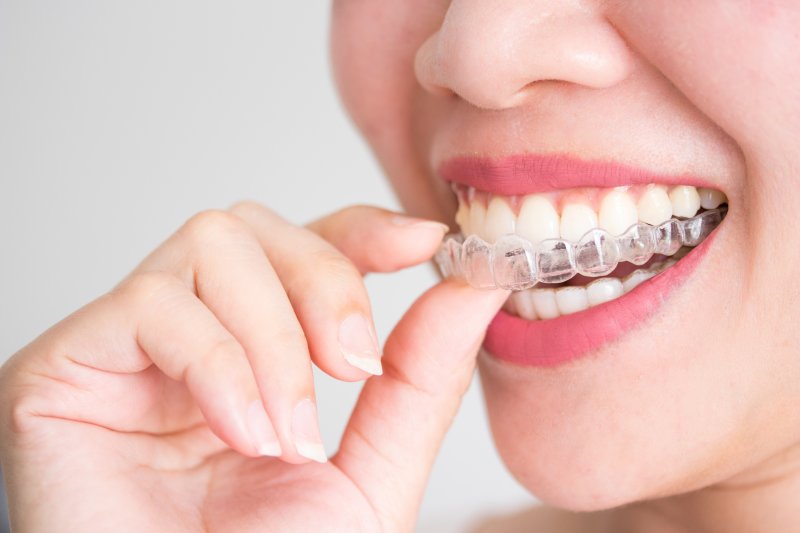 young woman putting on an Invisalign aligner